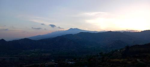 a view of a mountain range with the sun setting at Bluesky Apartment Naxos 3rd floor in Giardini Naxos