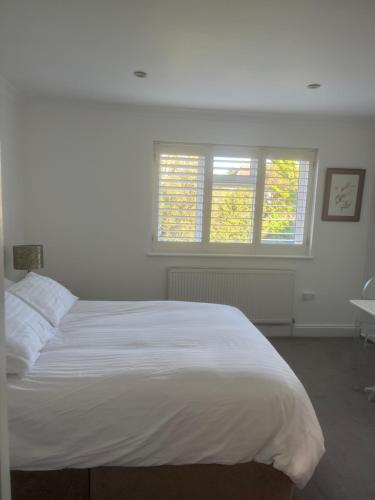 a bedroom with a white bed and two windows at Mayfield guest rooms in Bromley