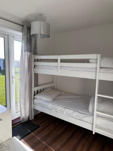two bunk beds in a room with a window at Grandad's Chalet, California Sands, Scratby, Great Yarmouth in Scratby