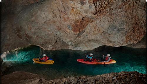 three people in kayaks in the water in a cave at Črjanski Raj in Črna na Koroškem