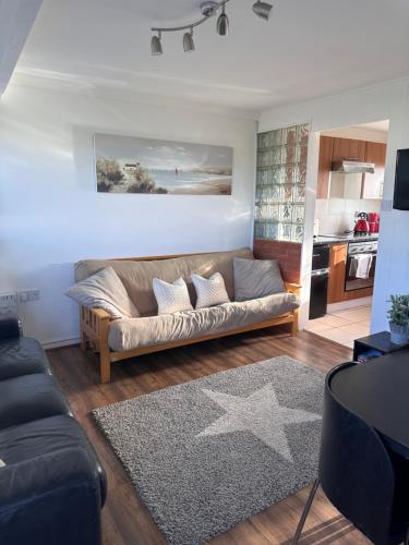 a living room with a couch and a kitchen at Grandad's Chalet, California Sands, Scratby, Great Yarmouth in Scratby