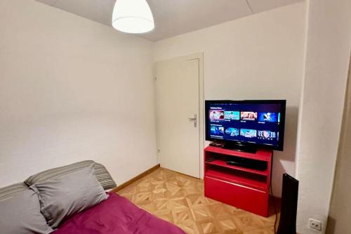 a bedroom with a flat screen tv on a red dresser at Wunderschöne Gartenwohnung in Zürich in Zürich