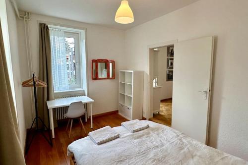 1 dormitorio con cama, escritorio y ventana en Wunderschöne Gartenwohnung in Zürich, en Zúrich