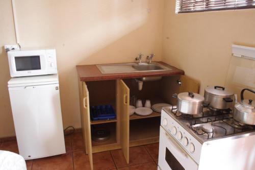 a small kitchen with a sink and a microwave at Rheotessa Deben in Dagbreek