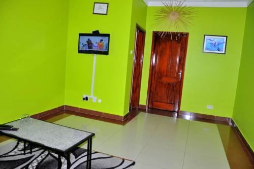 a green room with a table and a tv in it at Kisoro Homely Suites in Kisoro