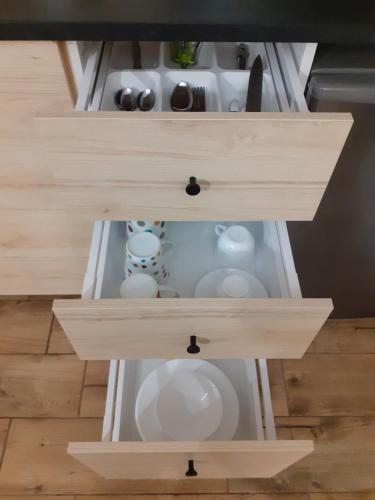 two drawers in a kitchen with white dishes at Old Town Apartment with a separate entrance in Kaunas
