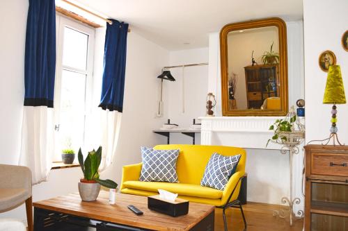 a living room with a yellow couch and a mirror at Manoir Drissia - Tours Centre, France in Saint-Avertin