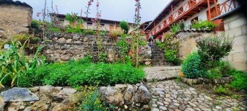 um jardim com uma parede de pedra com flores e plantas em Hospedaje Wayna Pakaq em Huanipaca