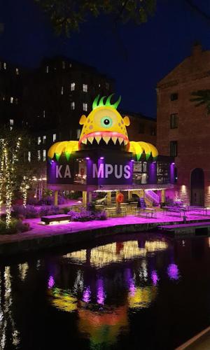 Una gran estatua de un monstruo se ilumina por la noche en Kampus, en Mánchester