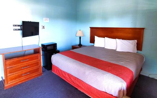 Habitación de hotel con cama y TV en Holiday Host Motel & RV Park, en Sonora