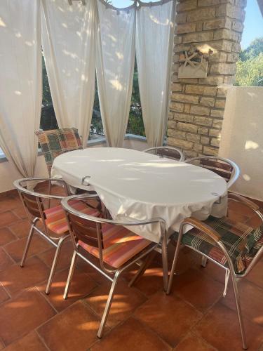 - une table et des chaises blanches dans une chambre avec fenêtre dans l'établissement Vila Franka, à Murter