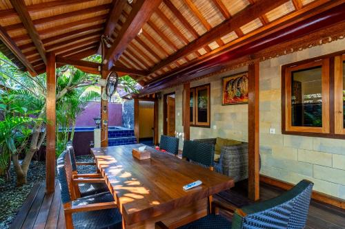 an outdoor dining room with a wooden table and chairs at Paradise Villa Gili Air in Gili Air