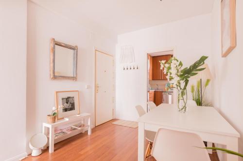 a white dining room with a white table and chairs at Cozy and Stylish Room with Natural Light and Vibrant Decor in Madrid