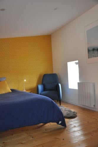 a bedroom with a bed and a blue chair at Maison du vigneron Saint-Martin in Le Cendre