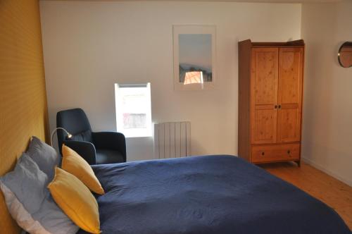 a bedroom with a blue bed and a chair at Maison du vigneron Saint-Martin in Le Cendre