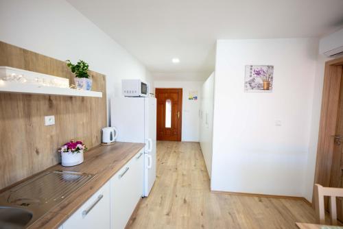 a kitchen with white cabinets and a wooden floor at PAPI Apartmán in Valtice