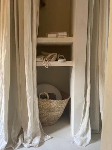 a shelf with a basket in a room with curtains at La Saracina in Pienza