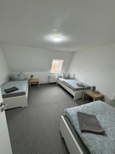 um quarto com três camas e uma janela em Tränental DG 1 em Stassfurt