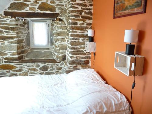 een slaapkamer met een stenen muur, een bed en een televisie bij Les Termes in Saint-Chély-dʼAubrac