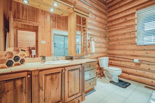 a log cabin bathroom with a toilet and a sink at Private Hot Tub Sauna Ski Indoor Pool Bee in Mille-Isles