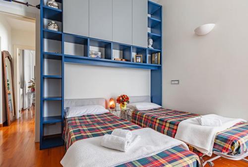 two beds in a room with blue shelving at Appartamento Chicco in zona elegante in Milan