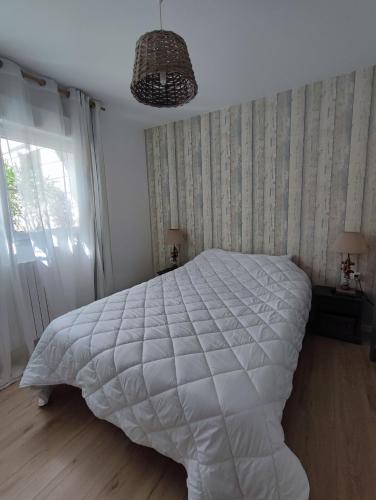 une chambre avec un grand lit blanc et une fenêtre dans l'établissement T2 jardin privatif et accès piscine, à Ploeren