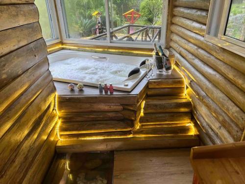 uma banheira de hidromassagem num chalé de madeira com uma janela em Piscina aquecida 32g, casa 3 quartos, + hidro em Santo Amaro da Imperatriz