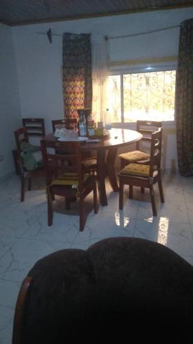una sala da pranzo con tavolo, sedie e finestra di villa yaoundé a Yaoundé