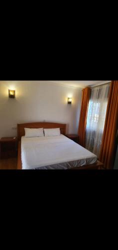 a bedroom with a bed with white sheets and a window at N et M Inn - Hébergement in Nsazomo