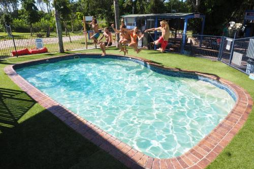 a group of people jumping in a swimming pool at Backpackers Inn On The Beach in Byron Bay