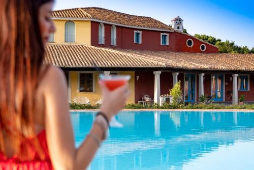 a woman holding a drink in front of a house at ECO HOTEL ORLANDO Sardegna in Villagrande Strisaili