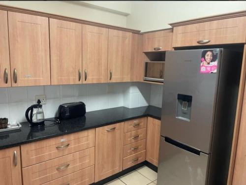a kitchen with wooden cabinets and a stainless steel refrigerator at Kennaway Court in East London
