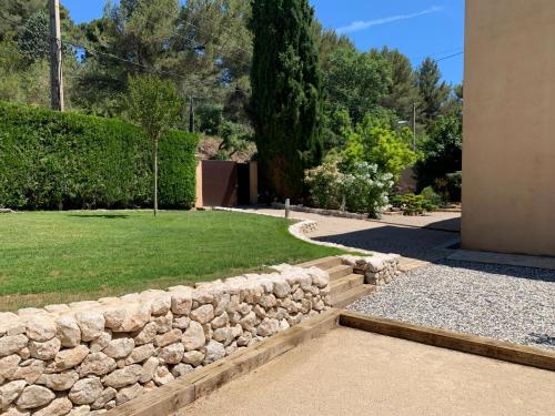 a stone retaining wall in a yard with a lawn at la grande villa in Aix-en-Provence
