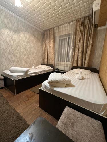 Duas camas individuais num quarto com cortinas em Tet-A-Tet em Qarasū