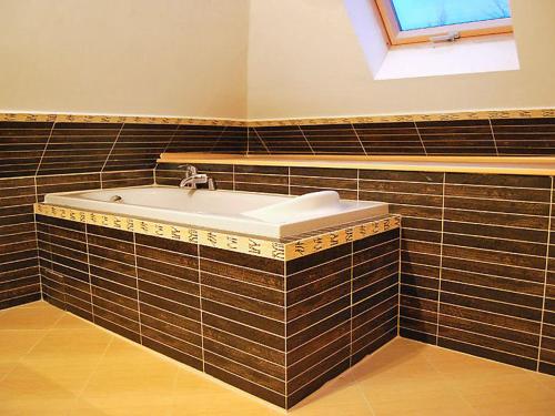 a bathroom with a bath tub with brown tiles at Wynajem willi z 3 sypialniami Sasino, in Sasino