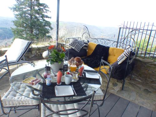 eine Terrasse mit einem Tisch, Stühlen und einem Sofa in der Unterkunft Louradou-sur-Ciel in Jouqueviel