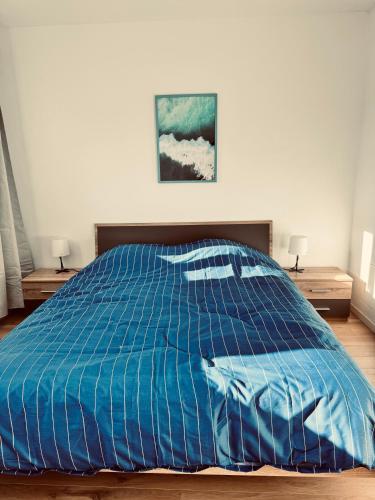 - un lit avec une couette bleue dans une chambre dans l'établissement Superbe appartement T3 rénové - Calais nord, à Calais