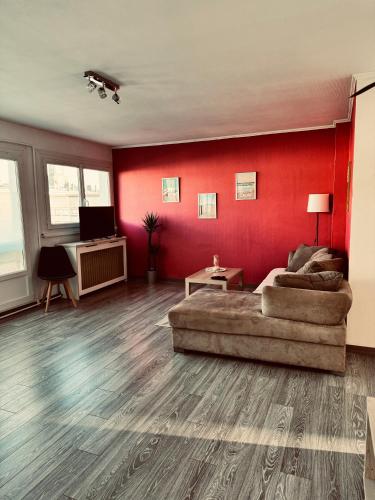 - un salon avec un canapé et un mur rouge dans l'établissement Superbe appartement T3 rénové - Calais nord, à Calais