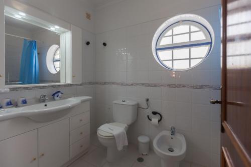 a bathroom with a toilet and a sink and a window at FLH Large Ericeira House with Terrace in Ericeira