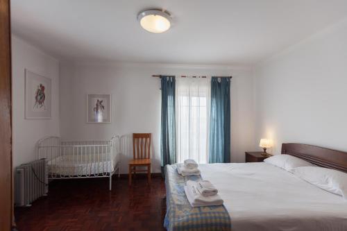 a bedroom with a large bed and a crib at FLH Large Ericeira House with Terrace in Ericeira