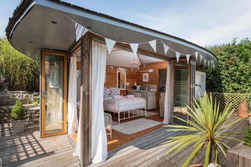 a covered deck with a bed and a kitchen at The Chandlery Shack, Cosy sleeps 2 Lyme Regis in Lyme Regis