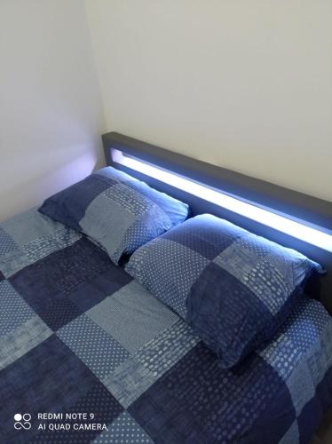 - un lit avec des oreillers bleus et un éclairage dans l'établissement Blessing, à Rosny-sous-Bois
