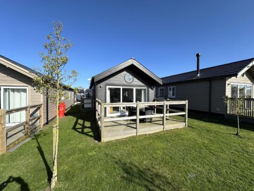 a small house with a fence in a yard at Bay Breeze - Part of the The Bay Filey Holiday Village with pool, gym and direct beach access, pub, restaurant, tennis and meadows walks in Filey