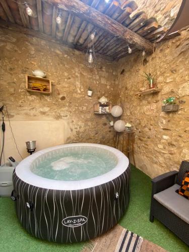 a hot tub in a room with a stone wall at Logement atypique avec jacuzzi inclus in Mallemort