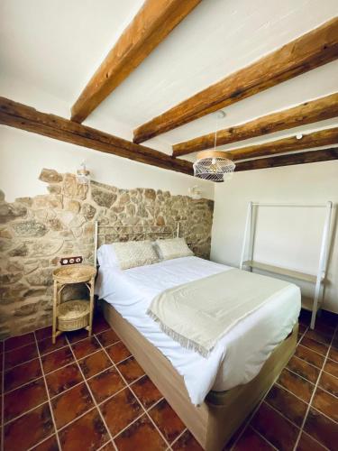 a bedroom with a bed and a stone wall at El Capricho de la Serranía II in Tragacete