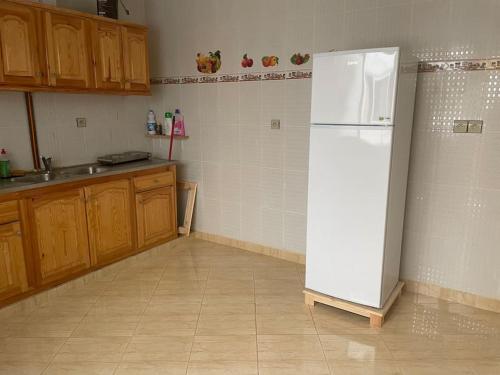 una cucina con frigorifero bianco e armadietti in legno di Een mooie familie appartement a Aït Farts
