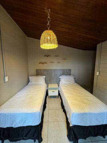 two beds in a bedroom with a chandelier at Pousada Piraúna in Fernando de Noronha