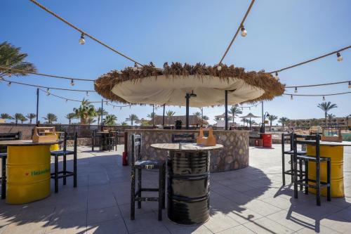 a patio with an umbrella and tables and chairs at Blend Elphistone Resort Marsa Alam in Abu Dabab