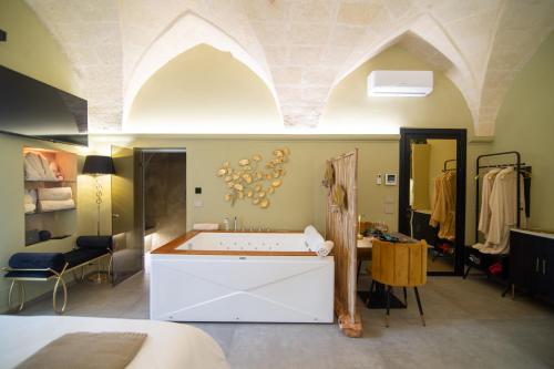 a bathroom with a tub in a room with a bed at Siramà Suite Deluxe in Oria