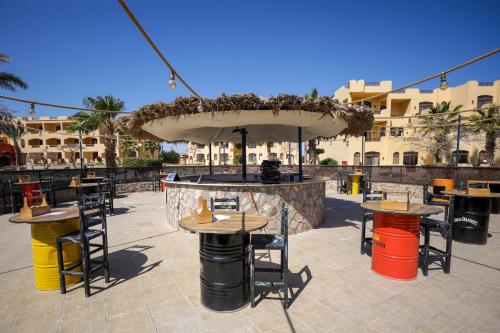 a patio with tables and chairs and an umbrella at Blend Elphistone Resort Marsa Alam in Abu Dabab